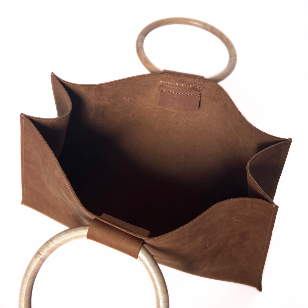 Open tote angle of tan grain leather tote with suede interior and oak wooden handles.